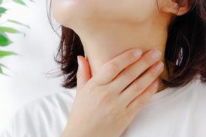のどを抑える女性